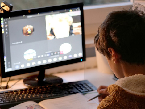 Ein Junge sitzt vor einem Computer und nimmt an einer Videokonferenz teil.