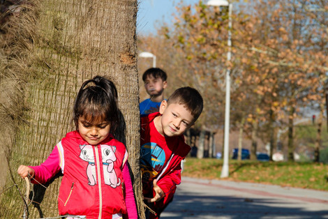 Ein Mädchen und zwei Jungen spielen Verstecken im Freien.